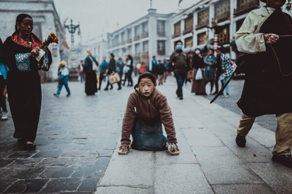 Girl Kneeling in Busy Street